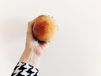 Close-up of hand holding apple against white background