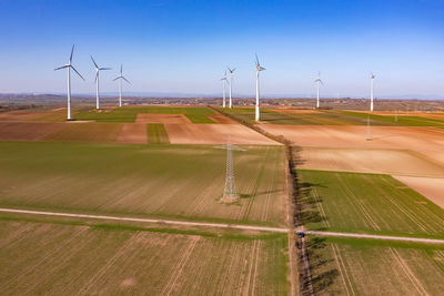 A power pole and many huge wind turbines on a field seen from above as a drone shot, energiewende