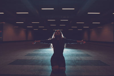 Young woman kneeling in underground walkway