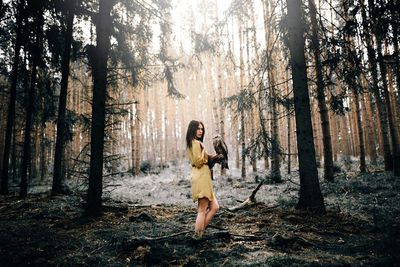 Full length of woman standing on tree trunk in forest