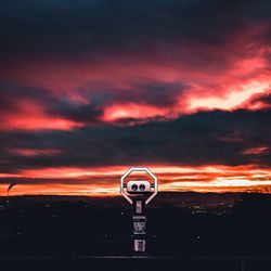 Silhouette information sign against orange sky