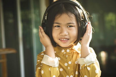 Portrait of smiling cute girl listening to music on headphones