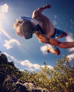 Young man with snorkel while jumping against sky