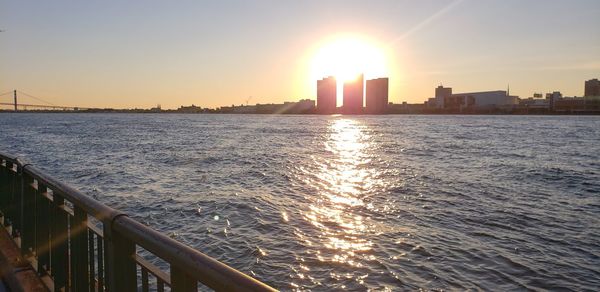 Scenic view of sea by buildings against sky during sunset