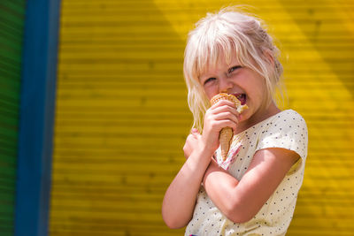 Portrait of girl eating ice cream cone while standing outdoors