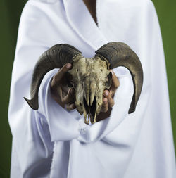 The sheep's skull is held by a mysterious white figure, it looks scary