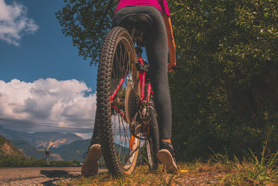 A low-angle close-up of a female cyclist riding a bicycle on a rural road in the alps mountains