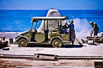 Rear view of people working in sea against sky