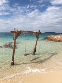 Deck chairs on beach against sky