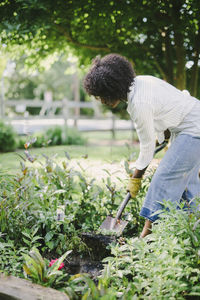 Woman digging soil with shovel in garden
