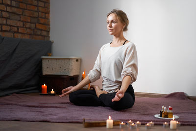 Young woman sitting on table against wall