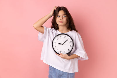 Portrait of woman standing against pink background