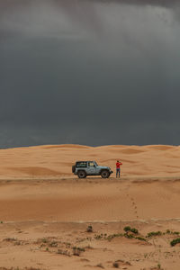 Woman gets out of her jeep to take pictures of desert microburst