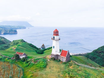 Lighthouse amidst sea and buildings against sky