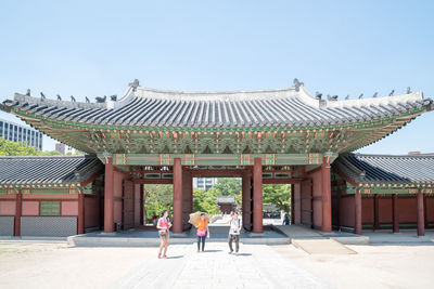 People standing on pavement at changdeokgung palace against sky