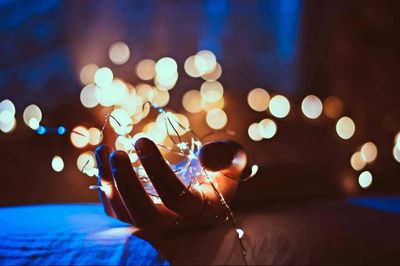 Close-up of hand holding illuminated lights at night