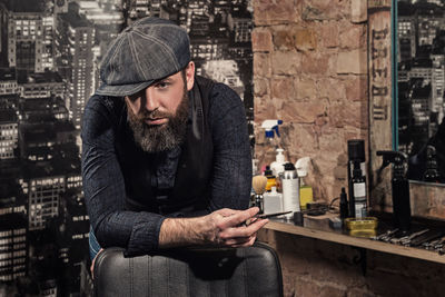 Portrait of young man using mobile phone while standing in cafe
