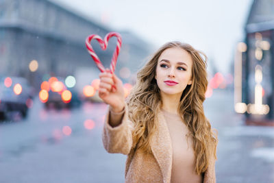 A sweet dreamy girl, a young woman holding a lollipop in the form of a heart on a winter day