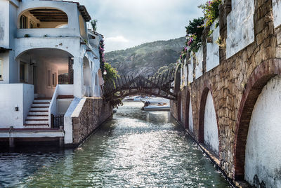 Bridge over canal amidst buildings against sky