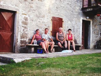 Portrait of happy friends sitting outside house