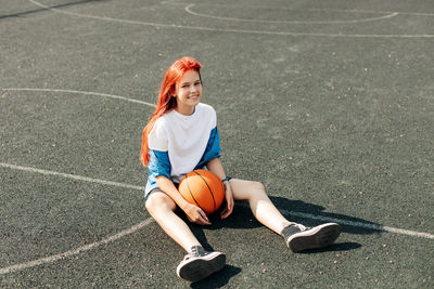 A charming teenage girl with a basketball is resting after a workout. a girl on the sports field. 