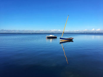 Boats moored on sea against blue sky