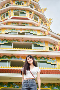 Portrait of a smiling young woman standing against wall