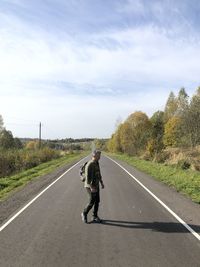 Rear view of man walking on road against sky