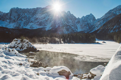 Scenic view of snow covered mountains against bright sun