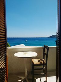 Chairs and table by swimming pool against clear blue sky