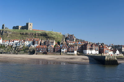 Sea by town against clear blue sky