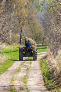 Old tractor driving on a dirt road in the spring