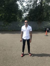 Full length portrait of young man standing against trees