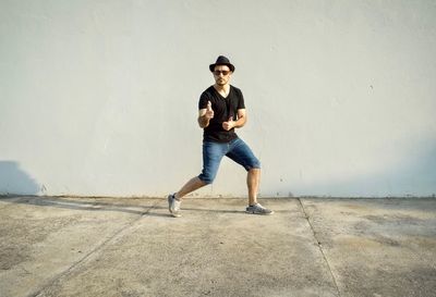 Full length portrait of man standing against wall