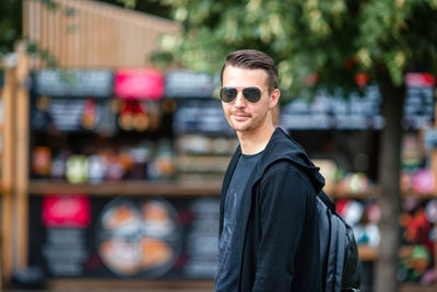 Portrait of young man wearing sunglasses standing outdoors