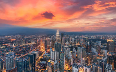 Aerial view of illuminated city buildings during sunset