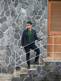 Portrait of young man standing against wall