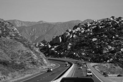 Cars on road by mountains against sky