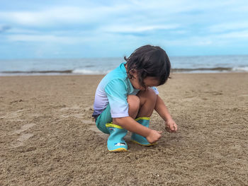 Rear view of boy on beach against sky