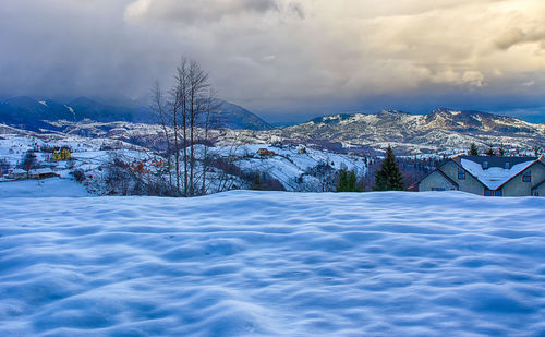 Snow covered landscape against cloudy sky