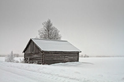 House on snow covered field against sky