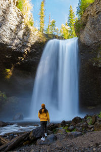 Rear view of woman standing against waterfall