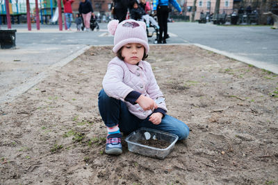 Girl digging in the dirt on the playground on a foggy fall day