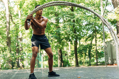 Full length of shirtless athlete exercising on footpath