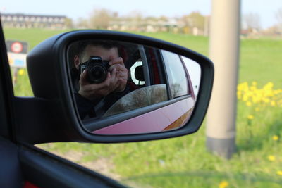 Portrait of man photographing through side-view mirror