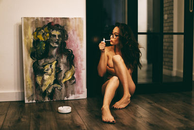 Young woman sitting on wooden floor at home