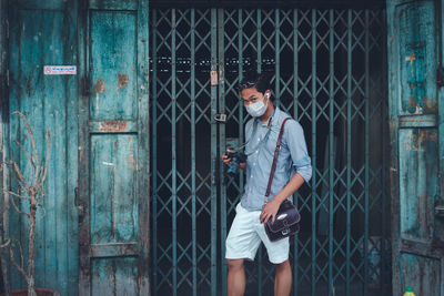 Portrait of young man standing against wall