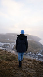 Rear view of man standing on mountain against sky