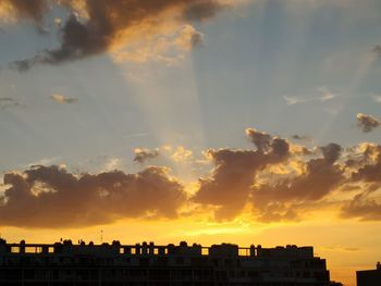 Low angle view of silhouette buildings against dramatic sky