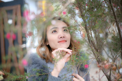 Portrait of woman with pink flowers against trees